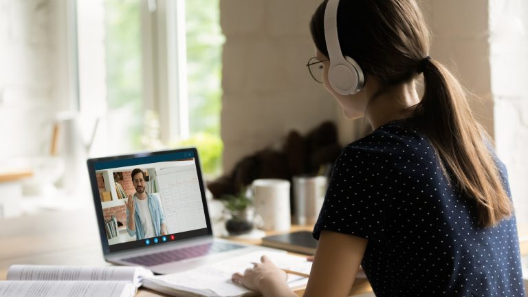 Happy young caucasian girl in headphones learning foreign language online.